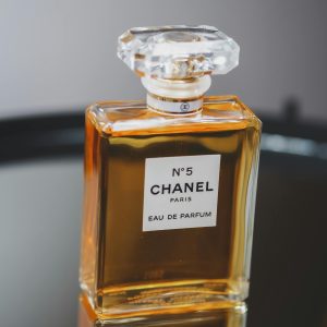 Close-up of Chanel No. 5 perfume bottle on reflective surface, highlighting elegance and luxury.