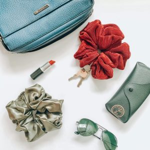 Overhead view of fashion items including scrunchies, purse, sunglasses, and more.