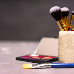 A stylish display of makeup brushes in a holder alongside a colorful palette.