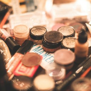 A vibrant collection of cosmetics including eyeshadows, lipsticks, and brushes on a table.